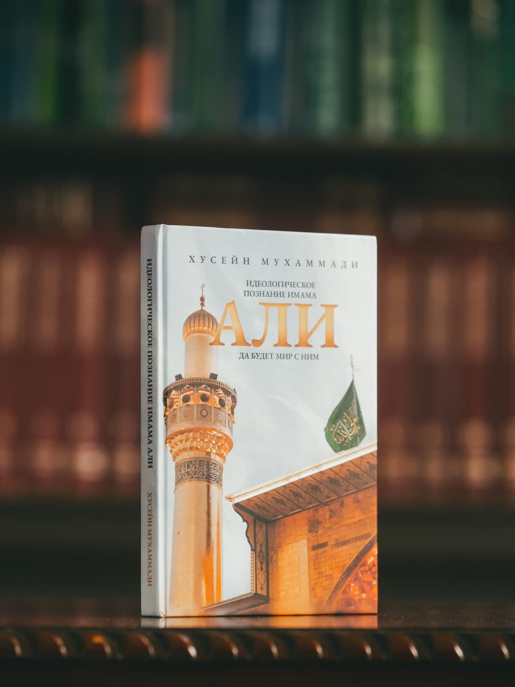 Книга «Идеологическое познание Имама Али» на фоне библиотеки