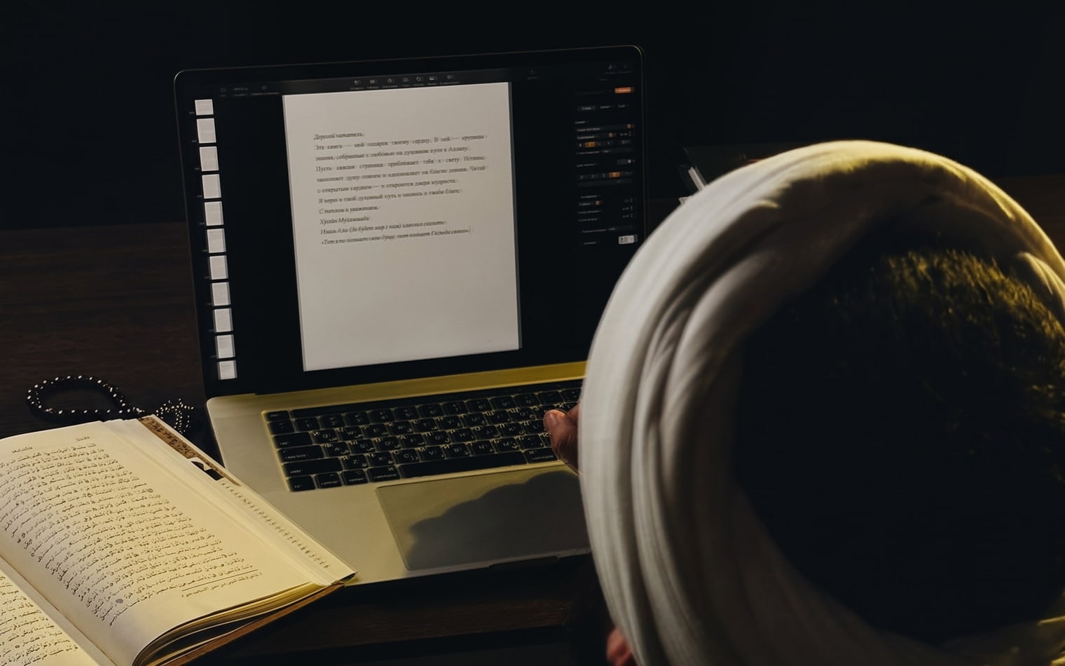 Учитель Хусейн за ноутбуком пишет письмо читателю, рядом раскрытая книга и чётки